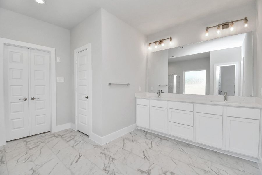 Elevate your daily routine at the elegant vanity, now equipped with double sinks, light countertops, modern hardware, and beautiful vanity lights. Sample photo of completed home with similar floor plan. Actual colors and selections may vary.