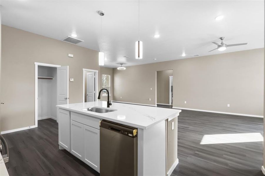 Kitchen with white cabinetry, dishwasher, sink, hanging light fixtures, and a kitchen island with sink