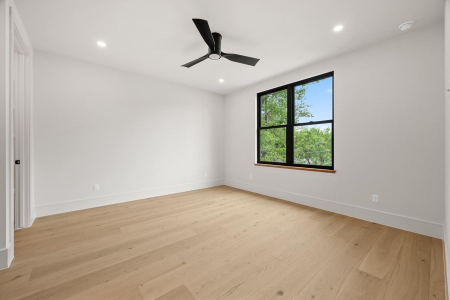 A minimalist design highlights clean lines, handsome wood flooring, and a large black-framed window.
