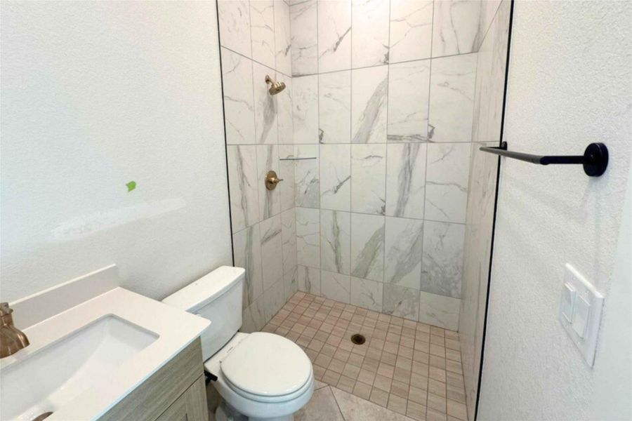 Bathroom featuring a textured wall, a stall shower, and vanity