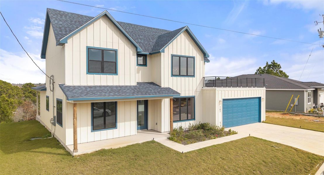 Modern inspired farmhouse featuring roof with shingles, board and batten siding, and a front lawn
