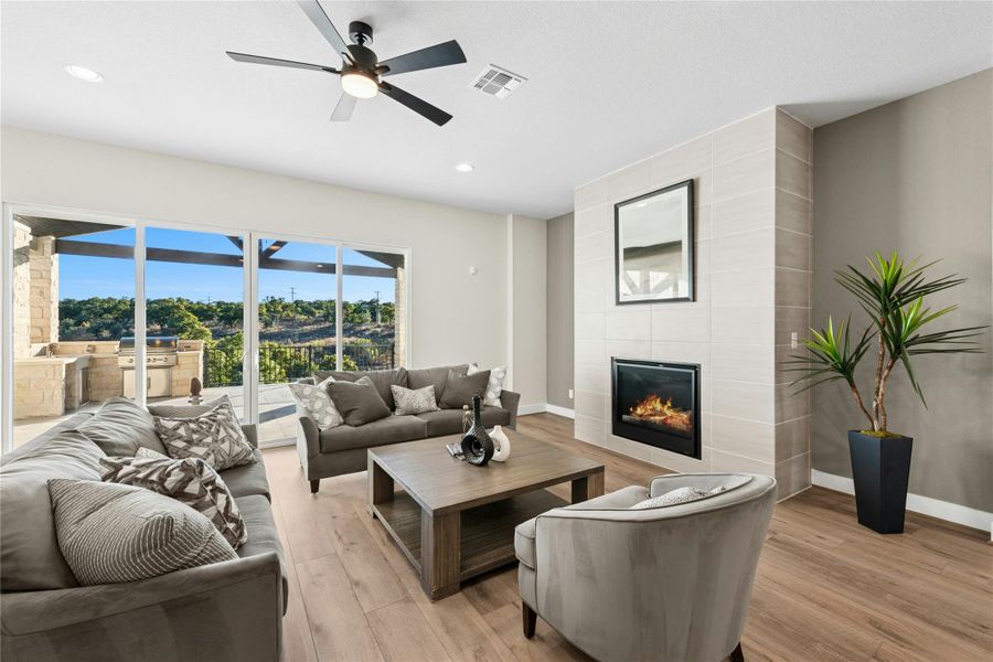 Living area with a fireplace, light wood-style floors, a ceiling fan, and recessed lighting Living area with a fireplace, light wood-style floors, a ceiling fan, and recessed lighting