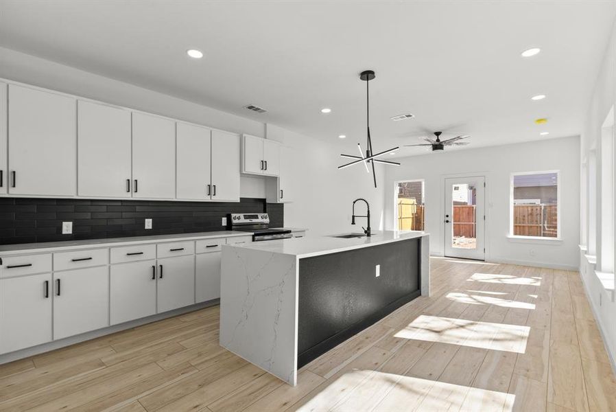 Kitchen featuring tasteful backsplash, stainless steel electric stove, light wood-style flooring, and a sink