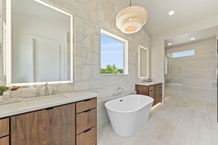 Full bath with two vanities, a soaking tub, a shower stall, tile walls, and recessed lighting