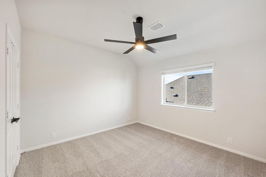 Empty bedroom with carpet flooring, vaulted ceiling, ceiling fan, and single window Empty bedroom with carpet flooring, vaulted ceiling, ceiling fan, and single window