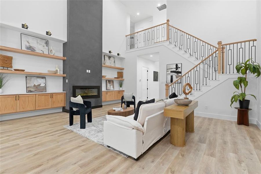 Living room with light wood finished floors, a fireplace, and a high ceiling