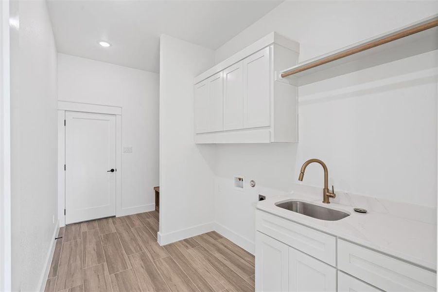 Laundry room with sink, cabinets, electric dryer hookup, hookup for a washing machine, and light wood-type flooring