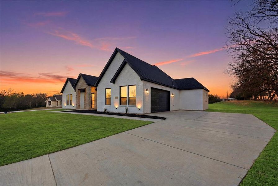 Modern inspired farmhouse with a front lawn, brick siding, an attached garage, and concrete driveway