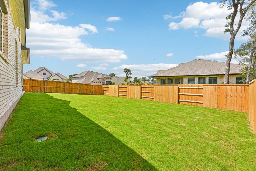 A generous, green lawn offers ample space for outdoor activities, fully enclosed by a sturdy privacy fence. A generous, green lawn offers ample space for outdoor activities, fully enclosed by a sturdy privacy fence.