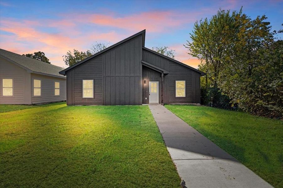 View of front of home with an outdoor structure and a yard