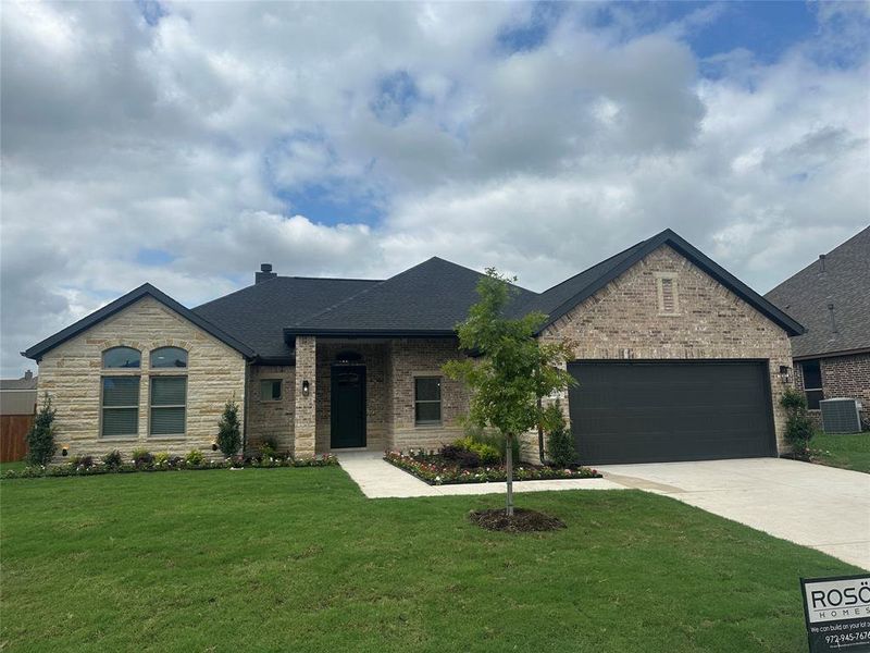 View of front of property featuring a garage, central AC, and a front lawn