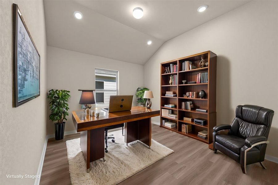 An inviting home office boasts a vaulted ceiling and ample built-in shelving, perfect for focused work.