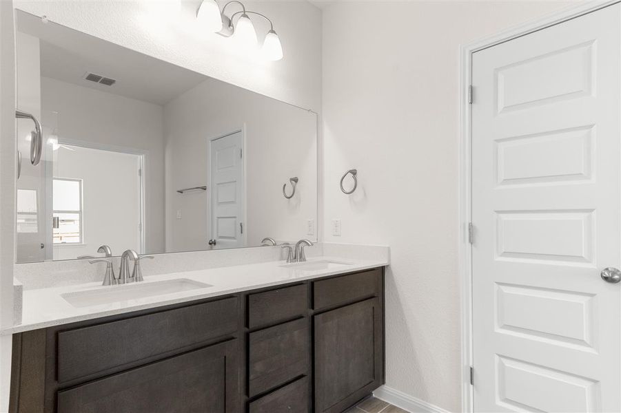Full bath featuring double vanity, a sink, baseboards, and visible vents
