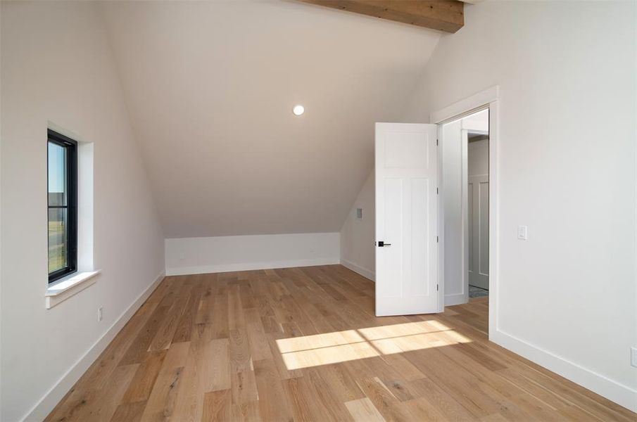 Bonus room featuring light hardwood / wood-style flooring, beamed ceiling, and high vaulted ceiling