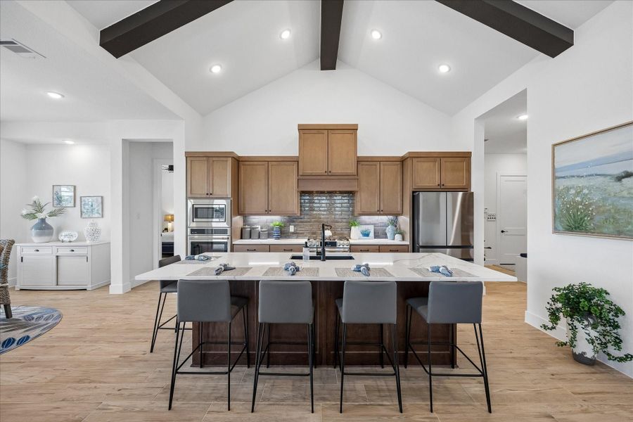 This expansive kitchen features a large granite countertop island that provides abundant seating and workspace. The open-concept layout creates a seamless flow between the kitchen, dining, and living areas, all unified by beautiful wood-plank tile flooring.