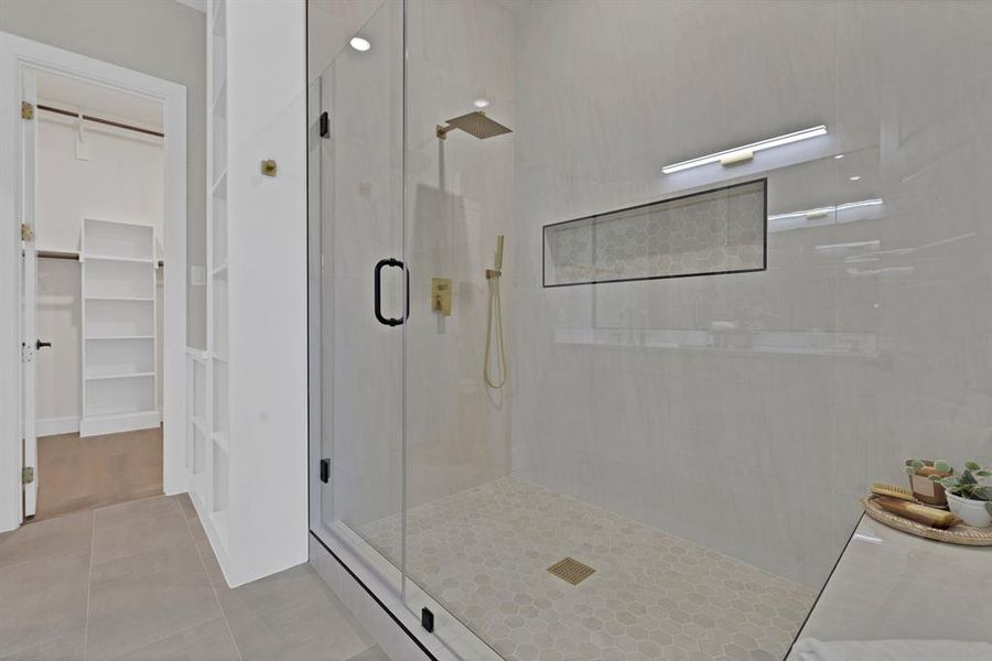 Bathroom featuring a stall shower, a walk in closet, and tile patterned flooring