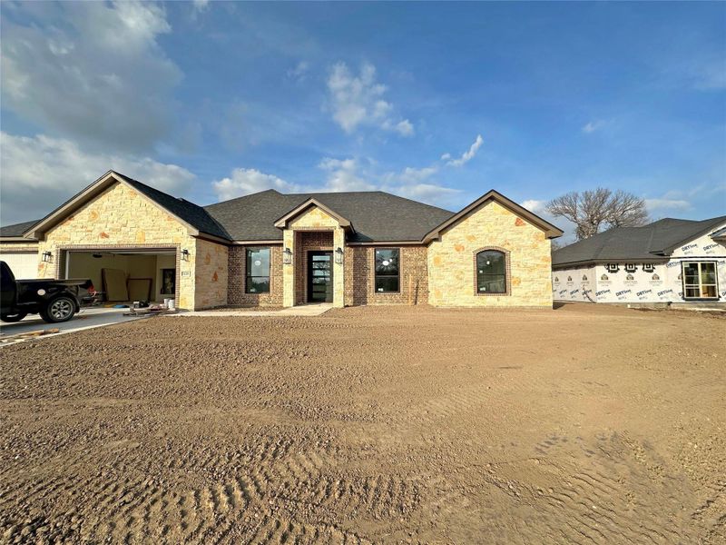 View of front facade with stone siding, an attached garage, and driveway