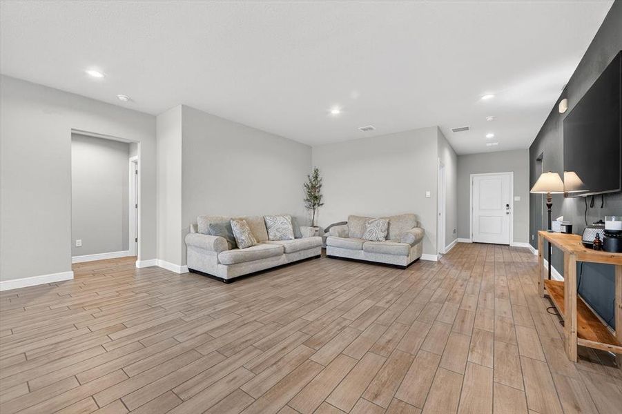 Spacious room featuring light wood-finish flooring, recessed lighting, and a neutral wall palette