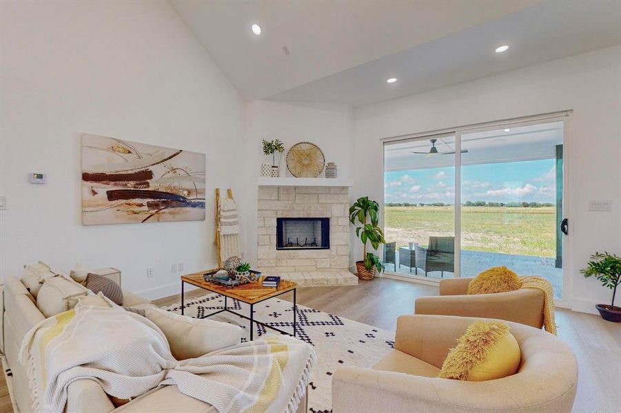 Living room with light hardwood / wood-style flooring, high vaulted ceiling, and a fireplace