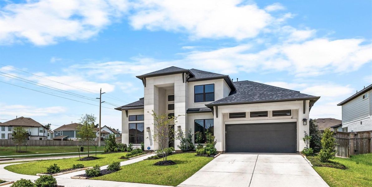 Stunning modern two-story home with a sleek facade, expansive driveway, and manicured landscaping in a serene neighborhood.