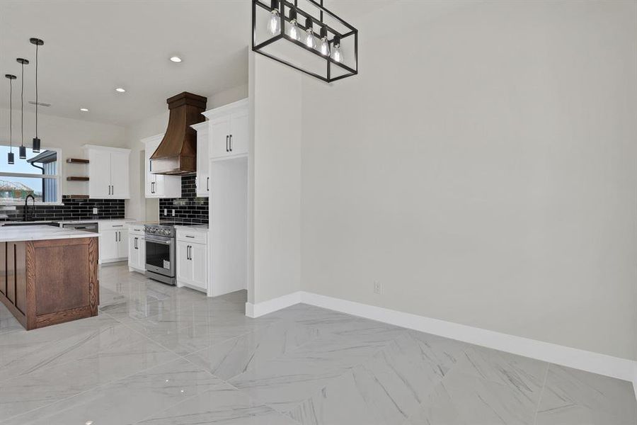 Kitchen with stainless steel appliances, hanging light fixtures, and white cabinets