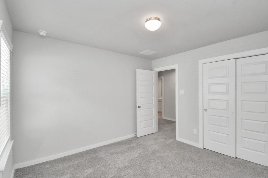 Secondary bedroom features plush carpeting, large windows that let in plenty of natural light, bright paint, and spacious closets.