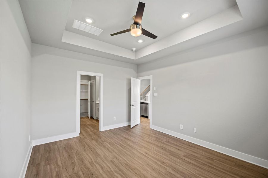 Luxurious main-level primary retreat featuring LVP, a tiered ceiling and a peaceful ambiance.