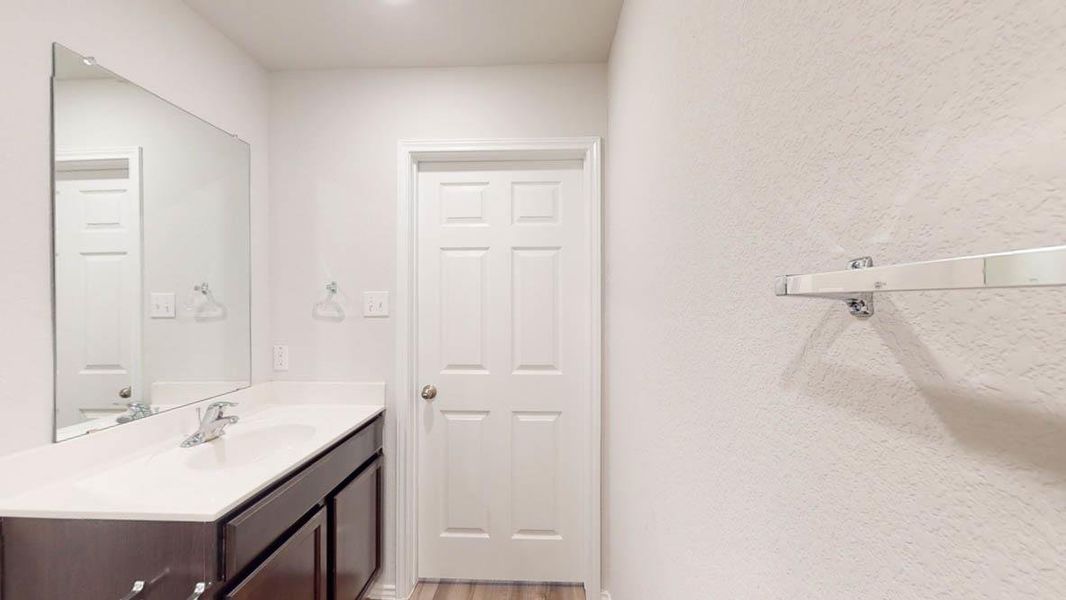 Bathroom vanity with an integrated sink, polished chrome faucet, and expansive wall-mounted mirror