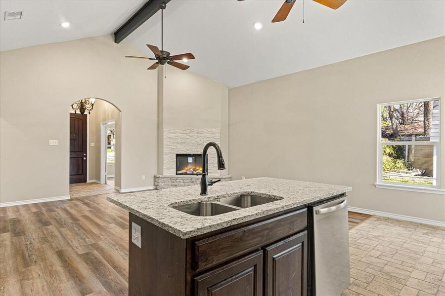 Kitchen with dark wood finish cabinets, arched walkways, a stone fireplace, open floor plan, and a ceiling fan  4403 N. Port Ridglea Ct. Granbury,TX 76049