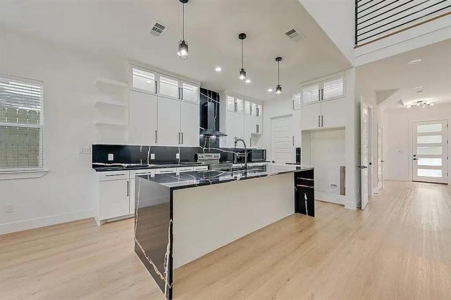 Modern kitchen featuring a waterfall island with patterned countertops, sleek white cabinetry, and stainless steel appliances
