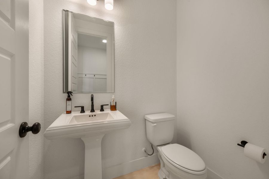 A pristine powder room offers a sleek pedestal sink and contemporary fixtures for guest convenience. A pristine powder room offers a sleek pedestal sink and contemporary fixtures for guest convenience.