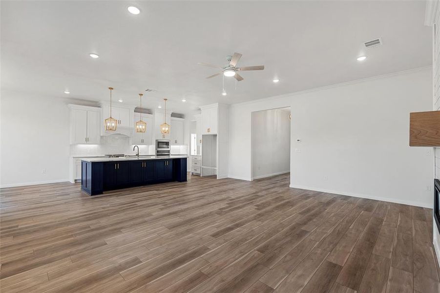 Unfurnished living room with a fireplace, a ceiling fan, ornamental molding, dark wood-style flooring, and recessed lighting