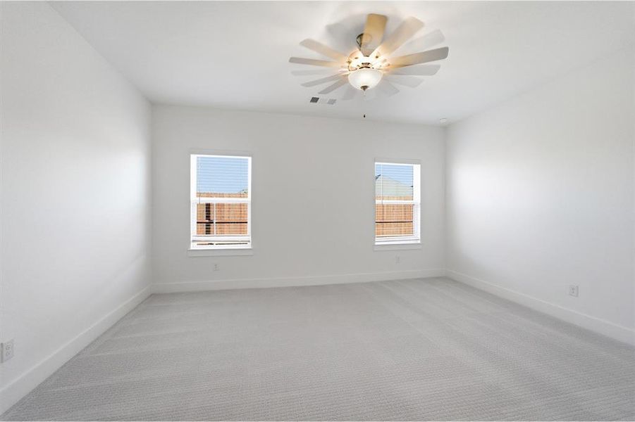 Spacious room featuring light gray carpeting, crisp white walls, two windows with white blinds, a white ceiling fan with integrated lighting, and white baseboards Spacious room featuring light gray carpeting, crisp white walls, two windows with white blinds, a white ceiling fan with integrated lighting, and white baseboards