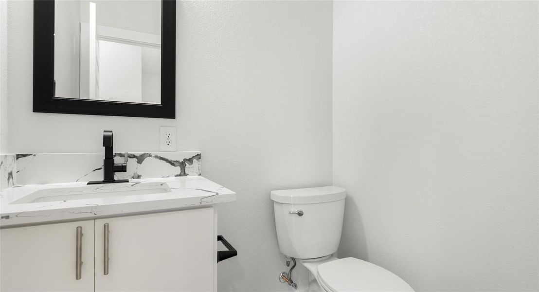 Half bathroom featuring vanity and toilet