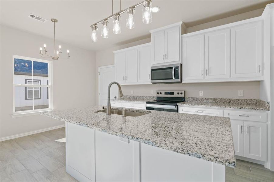 Kitchen with white cabinetry, sink, appliances with stainless steel finishes, and an island with sink Kitchen with white cabinetry, sink, appliances with stainless steel finishes, and an island with sink