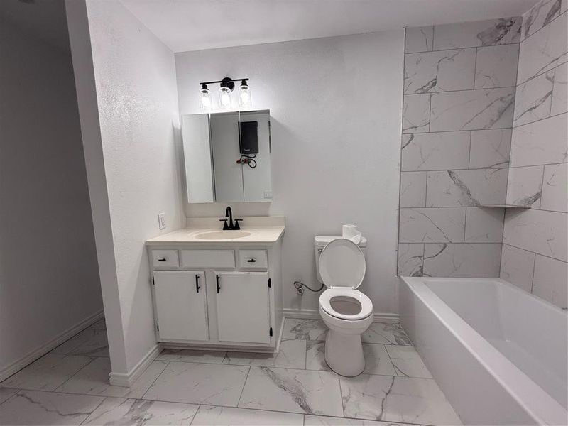 Full bathroom with vanity, light marble finish flooring, and shower / washtub combination
