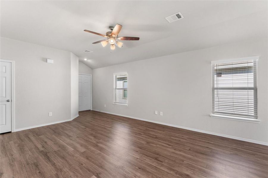 Spacious living area with ceiling fan, wood style flooring, and neutral wall colors. Spacious living area with ceiling fan, wood style flooring, and neutral wall colors.