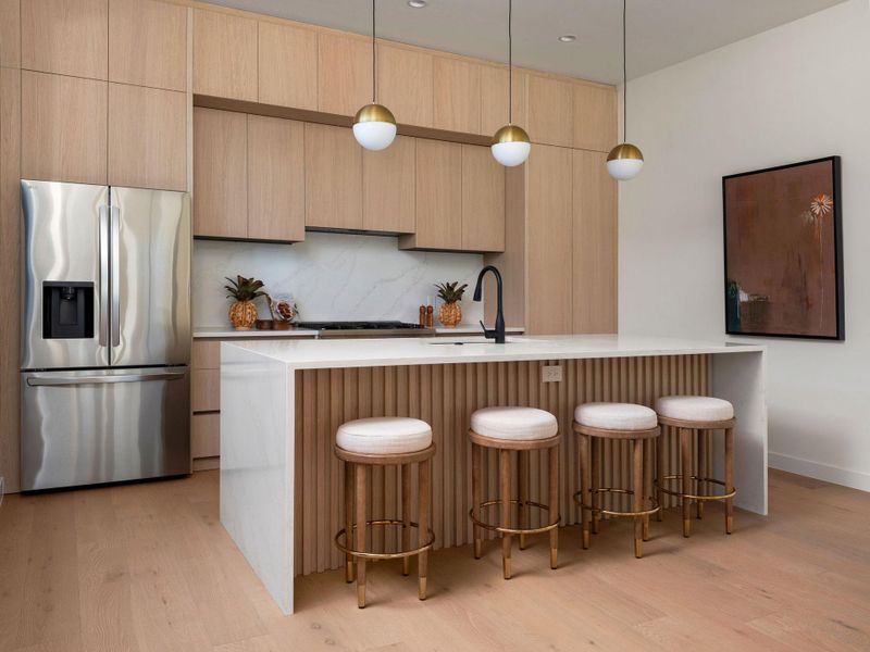 Kitchen with stainless steel refrigerator with ice dispenser, light stone countertops, pendant lighting, light wood finished floors, and modern cabinets