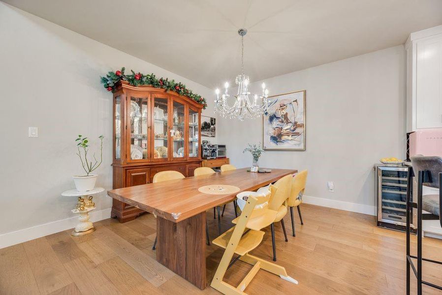 Dining room with light wood-style flooring, beverage cooler, and a chandelier
