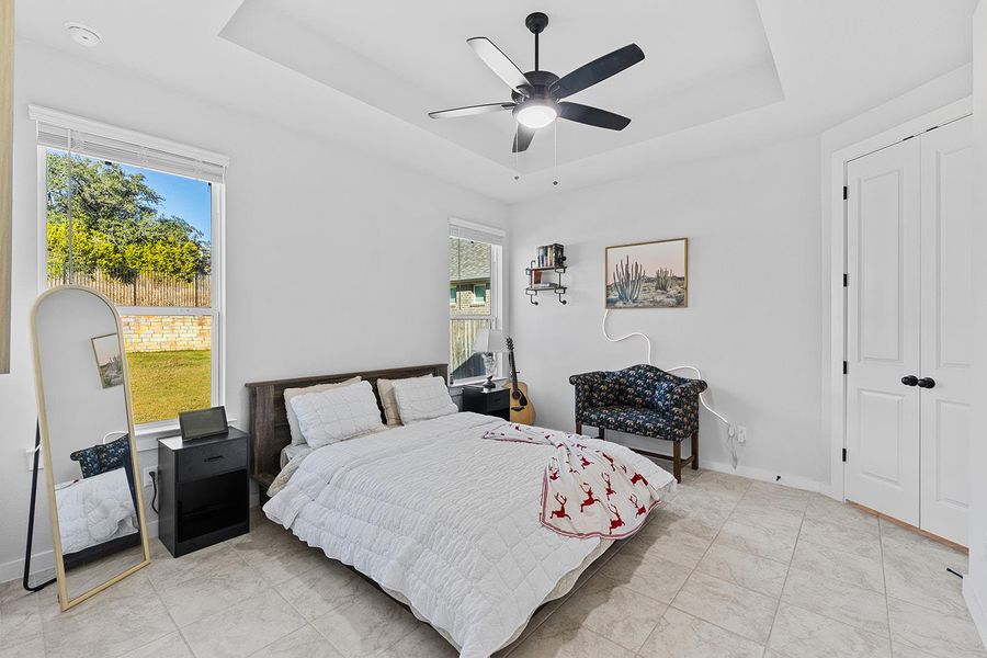 Bedroom featuring a tray ceiling, ceiling fan, and a closet