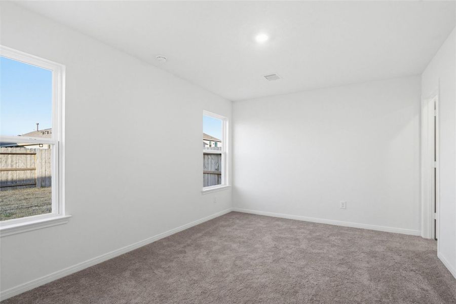 Come and unwind after a long day in this magnificent primary suite! This spacious room features plush carpet flooring, neutral paint, high ceilings, recessed lighting, and large windows!