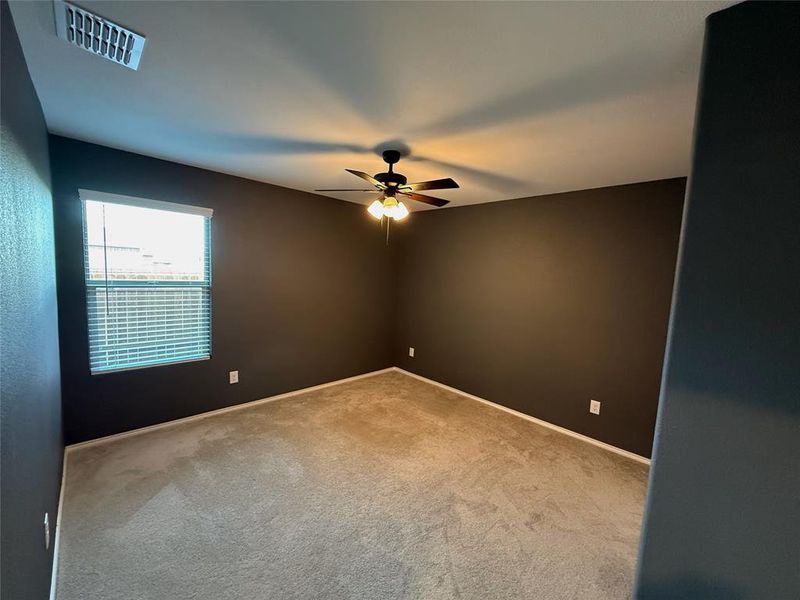 Spacious room featuring carpeting, a ceiling fan with integrated lighting, and a single window with blinds Spacious room featuring carpeting, a ceiling fan with integrated lighting, and a single window with blinds