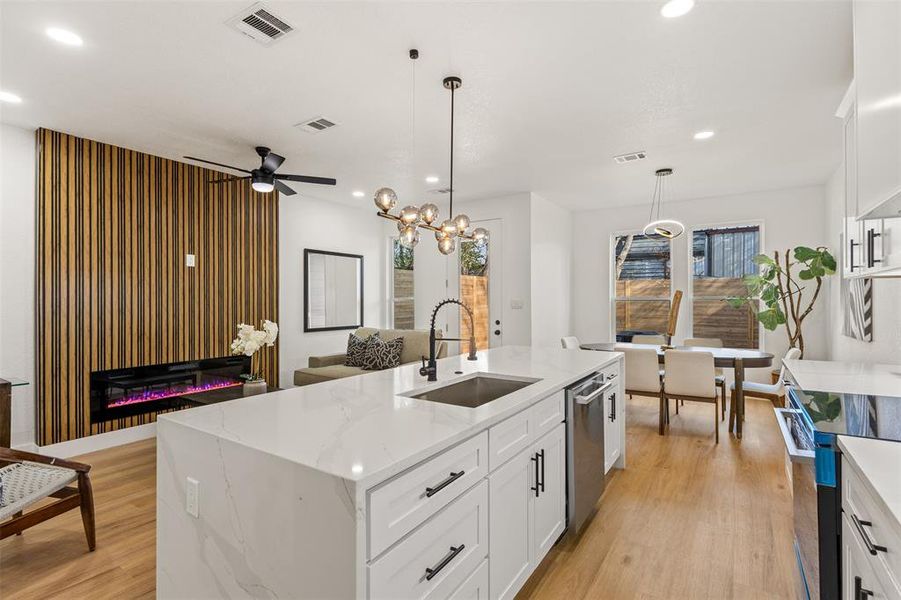 Kitchen with an island with sink, white cabinetry, light stone countertops, electric range, and light wood finished floors