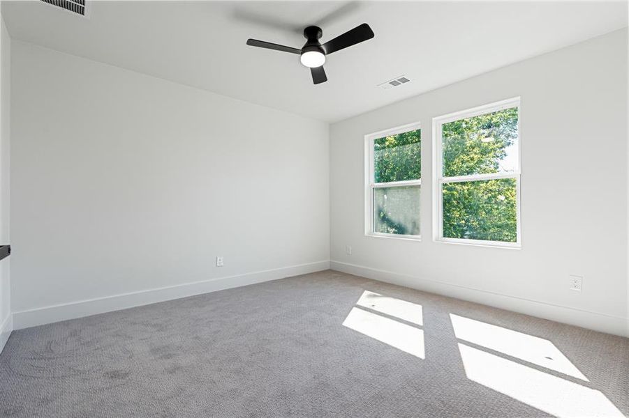 Carpeted empty room with a ceiling fan and baseboards