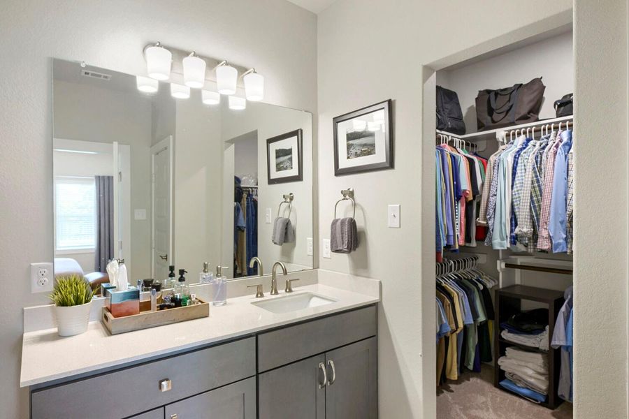 A well-organized vanity with a large mirror complements the adjacent walk-in closet. A well-organized vanity with a large mirror complements the adjacent walk-in closet.