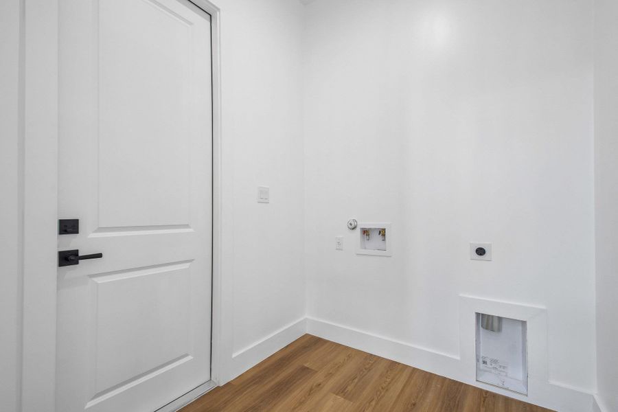 Clean lines and durable wood flooring define this utility space equipped with laundry hookups. Clean lines and durable wood flooring define this utility space equipped with laundry hookups.