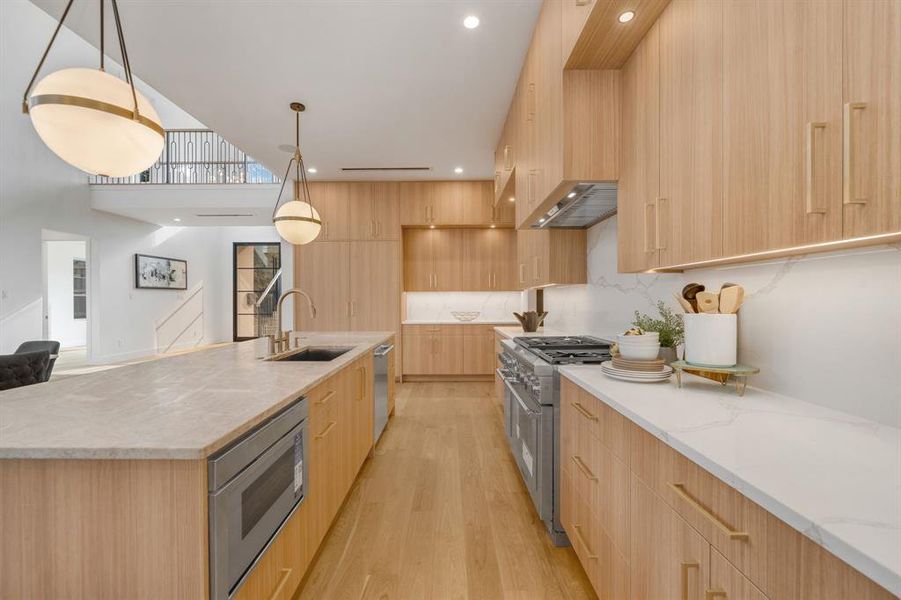 Kitchen featuring modern cabinets, light stone counters, appliances with stainless steel finishes, light wood-type flooring, and recessed lighting Kitchen featuring modern cabinets, light stone counters, appliances with stainless steel finishes, light wood-type flooring, and recessed lighting