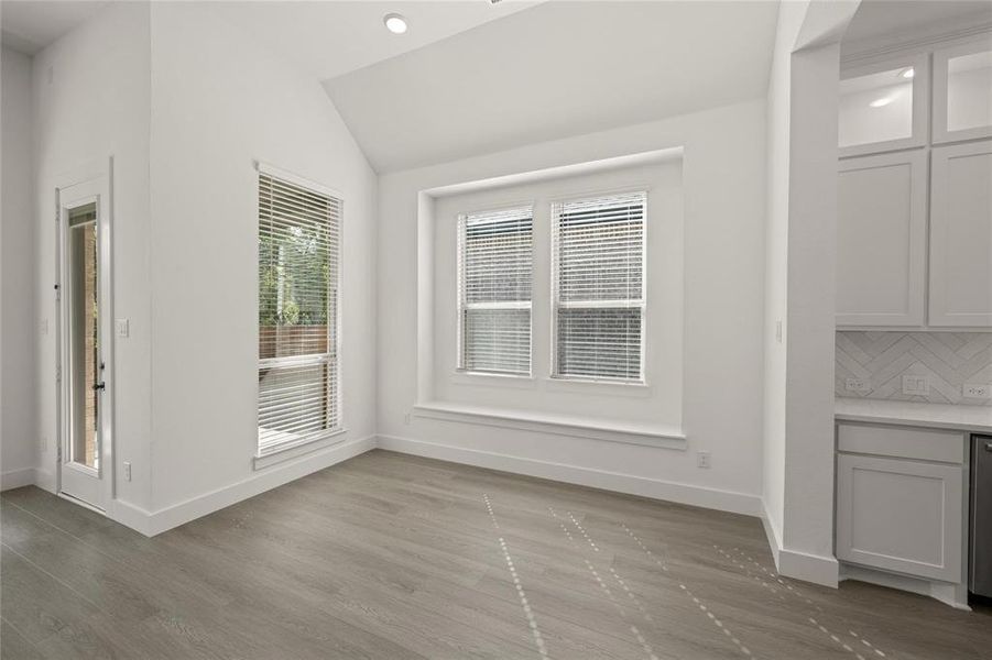 Unfurnished dining area featuring vaulted ceiling, dark wood-style flooring, and recessed lighting