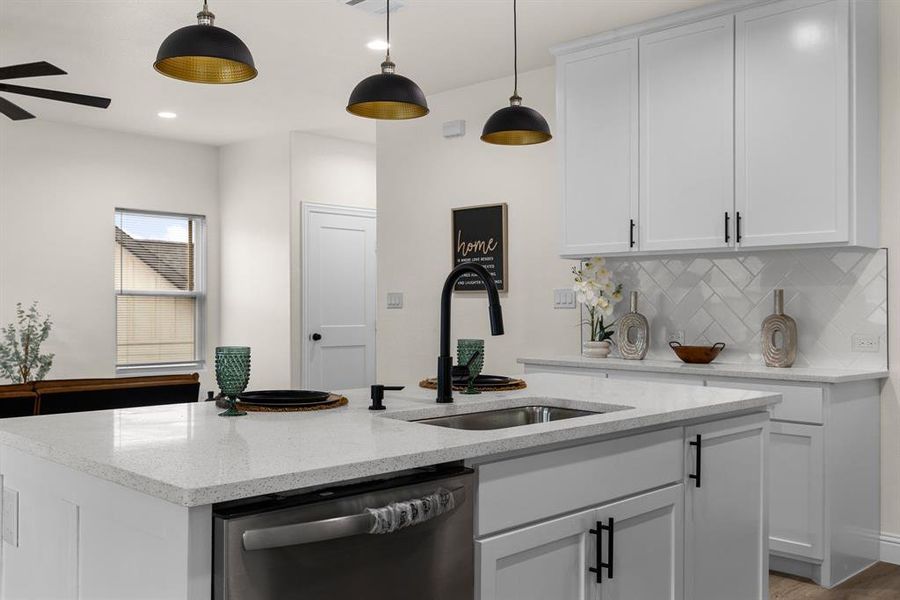 Kitchen with a kitchen island with sink, dishwasher, sink, and light stone countertops