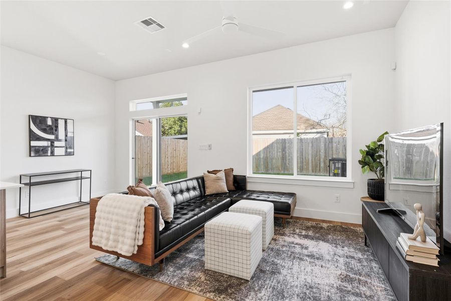Large sliding glass doors connect the living room to a covered patio, with oversized windows bringing in natural light.